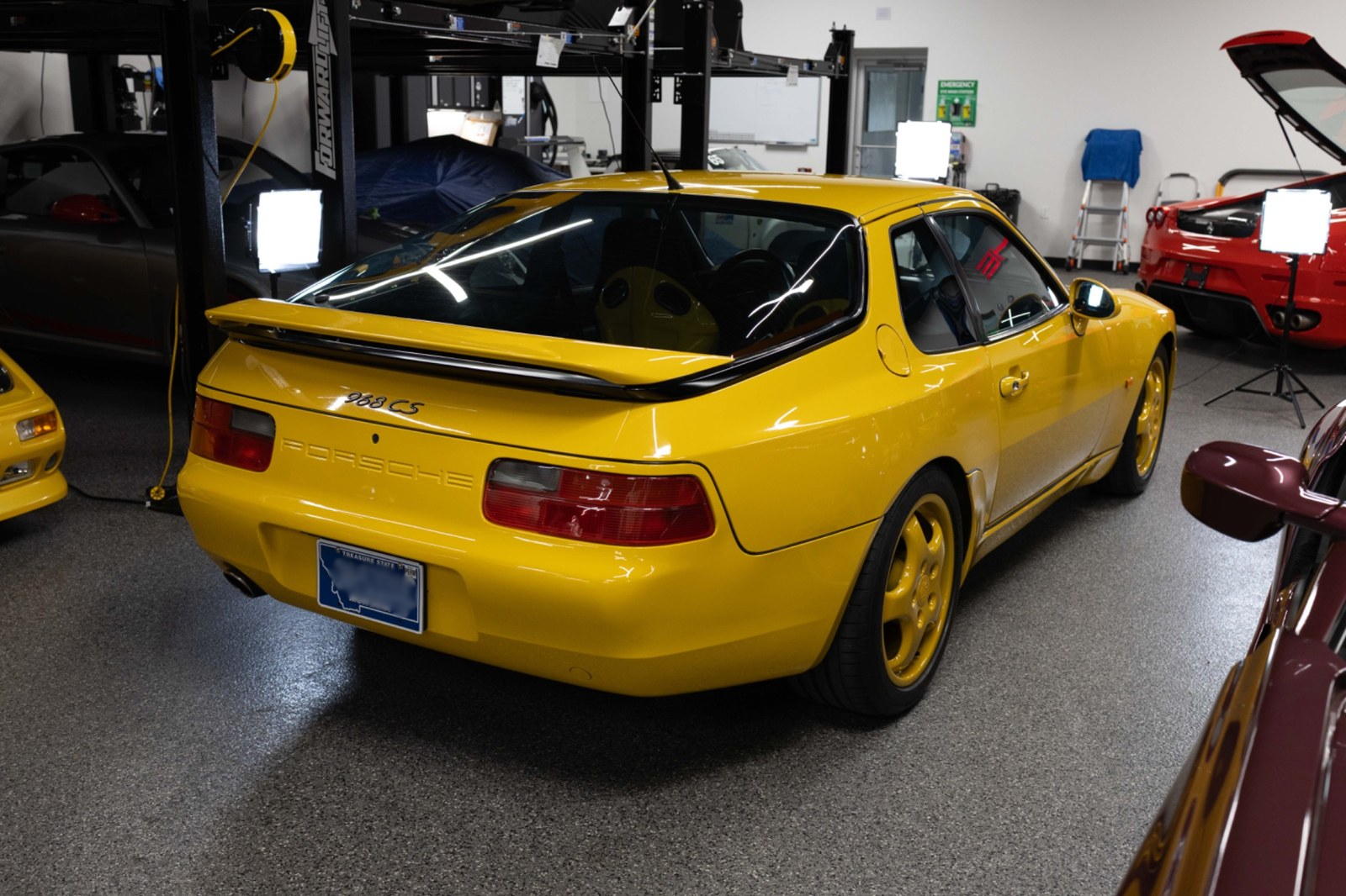 Speed Yellow Porsche 968 Club Sport rear three-quarter view in a shop